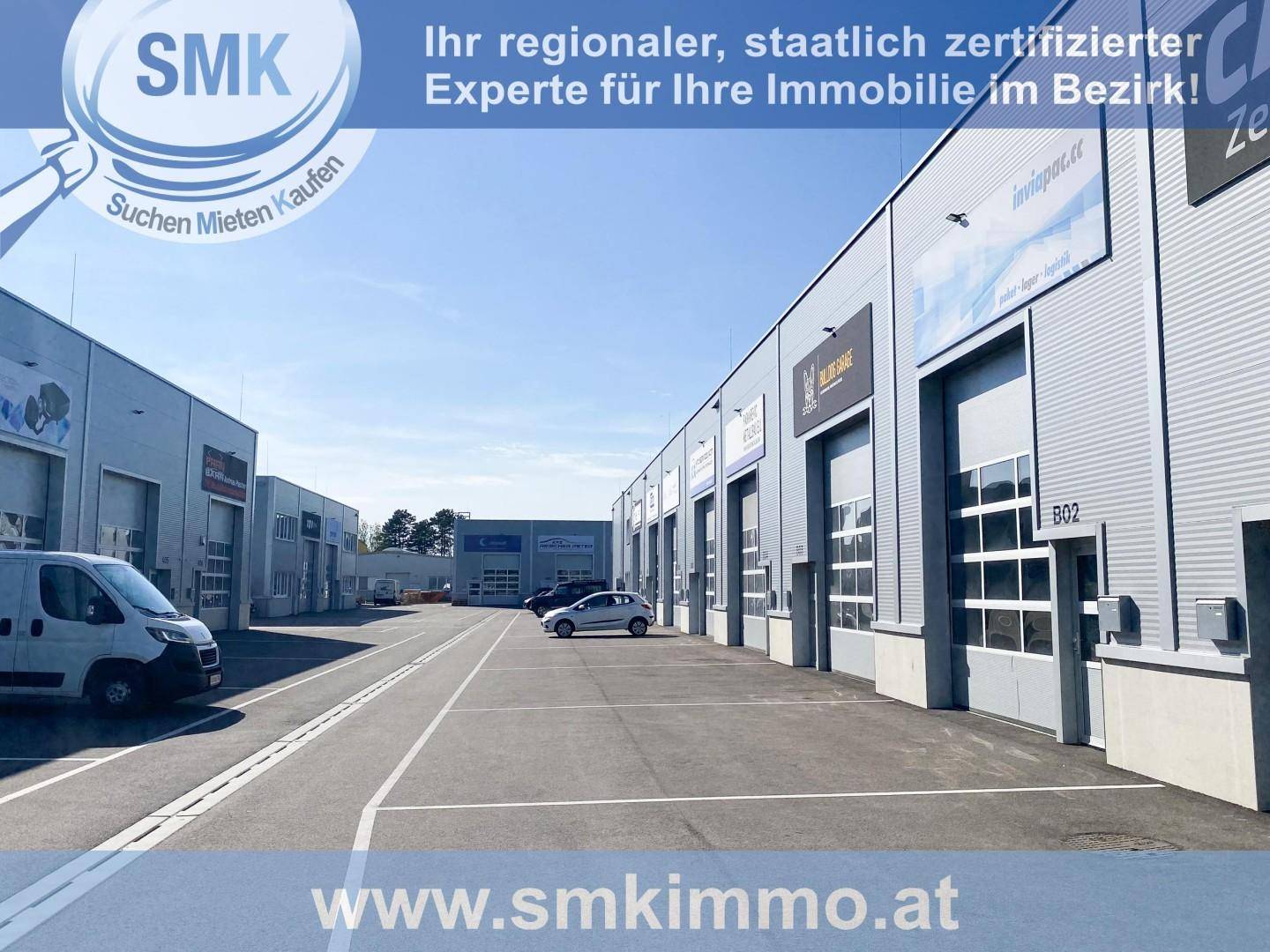 Reihe von modernen Gewerbegebäuden mit Parkplätzen unter blauem Himmel.