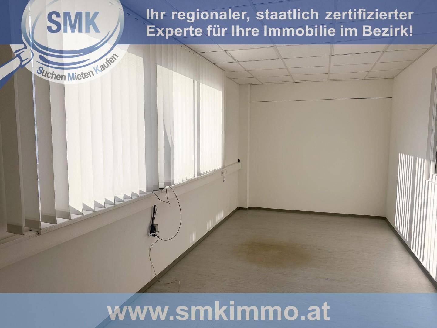 Leerer Büroraum mit weißen Wänden, Vinylboden und vertikalen Jalousien an den Fenstern.