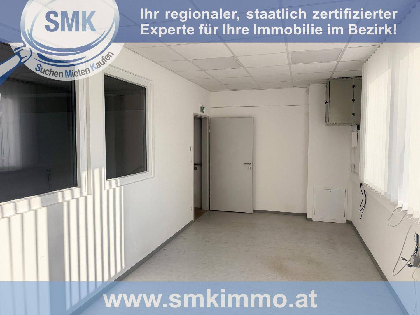 Heller Büroraum mit weißen Wänden, abgehängter Decke und Jalousien an den Fenstern.
