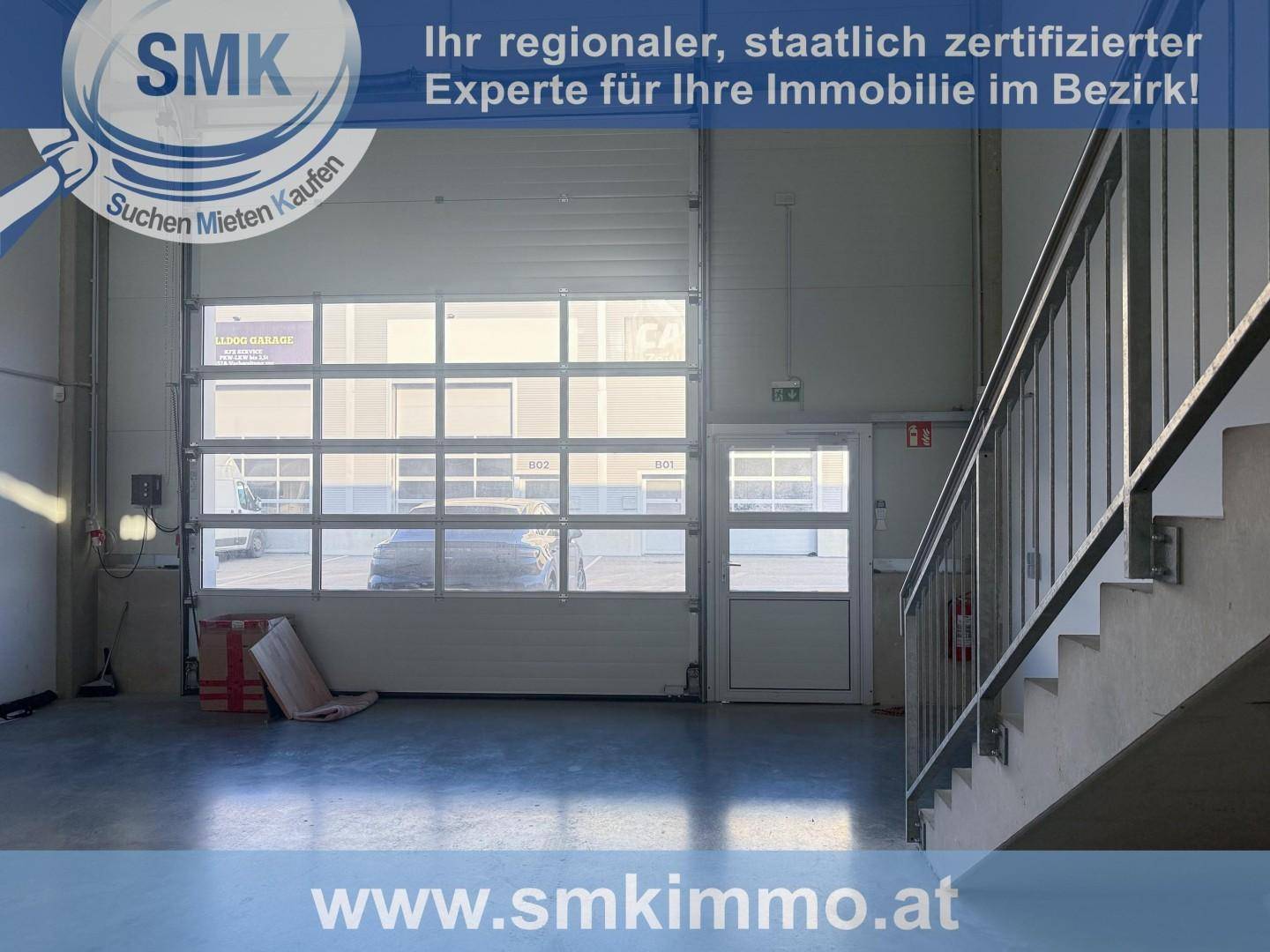 Heller Innenraum einer Gewerbehalle mit großem Rolltor und viel Tageslicht durch Fenster.