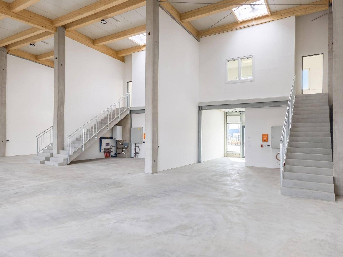 Geräumige Gewerbefläche mit hohen Decken, Holzbalken und mehreren Treppenaufgängen.
