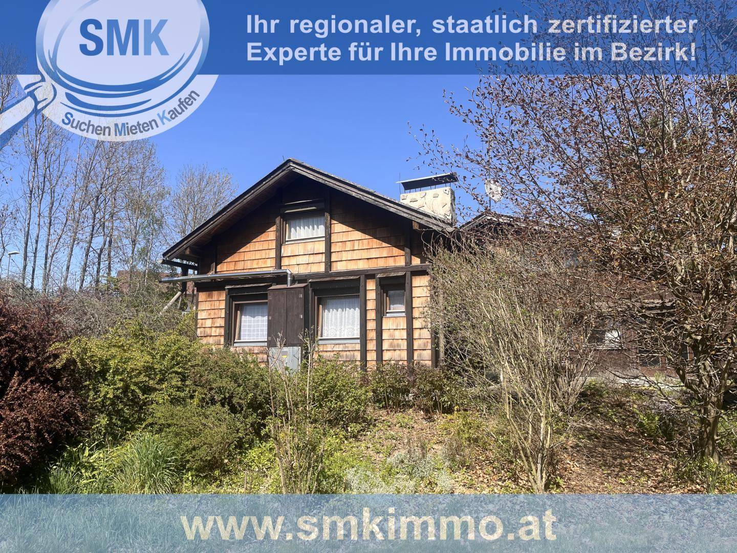 Charmantes Holzhaus mit Holzschindelfassade, eingebettet in eine grüne Landschaft.