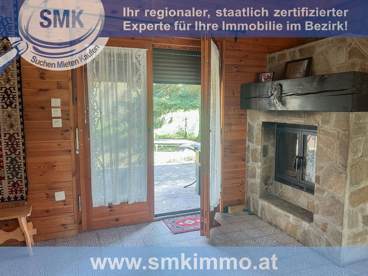 Gemütlicher Wohnbereich mit großem Steinkamin und Zugang zur Terrasse.