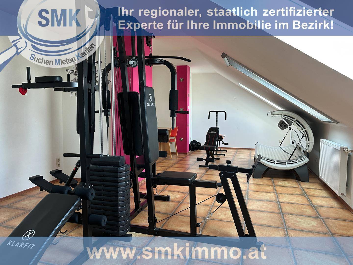 Geräumiger Fitnessraum im Dachgeschoss mit verschiedenen Trainingsgeräten und Schrägdach.