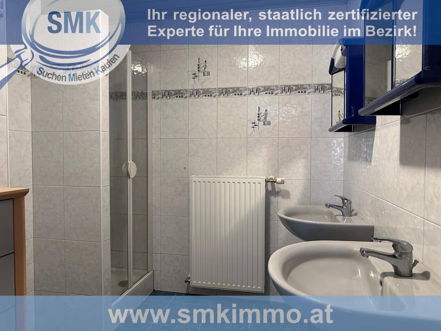 Badezimmer mit zwei Waschbecken, Duschkabine und hellen Wand- und Bodenfliesen.