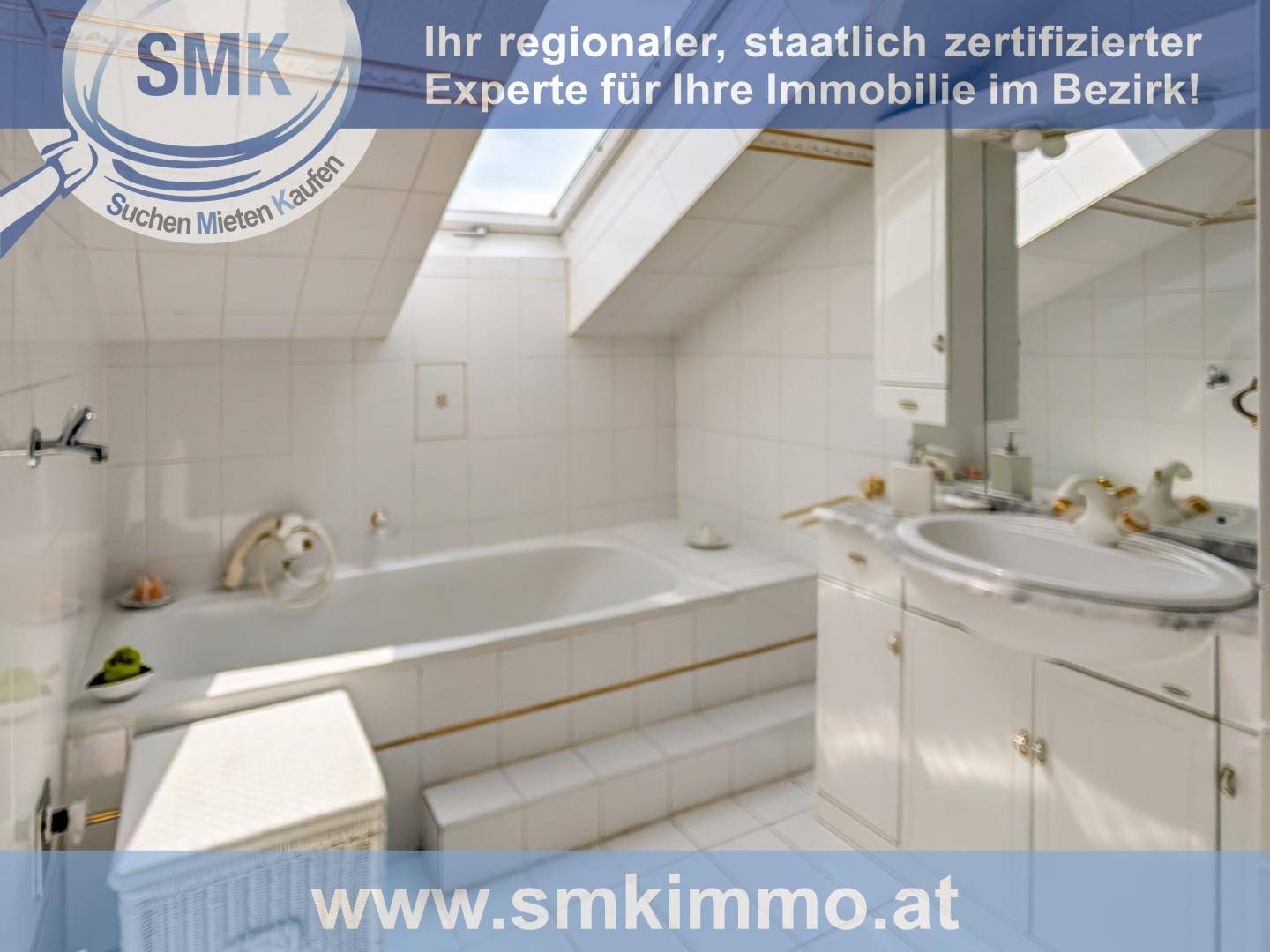 Badezimmer im Dachgeschoss mit Badewanne, Waschbecken, weißen Fliesen und Dachfenster.