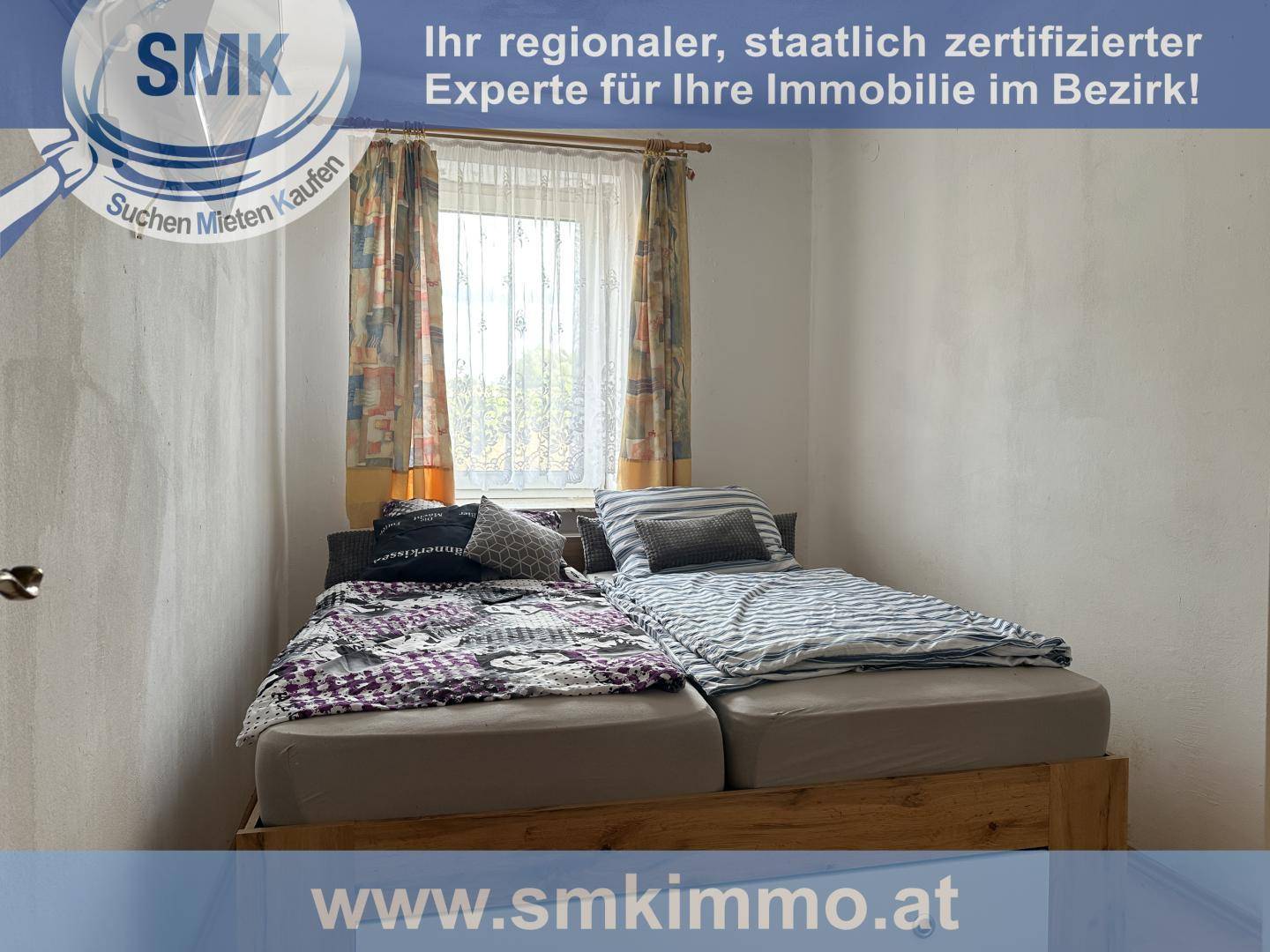 Schlafzimmer mit zwei Einzelbetten, einem Fenster und schlichten Wänden.