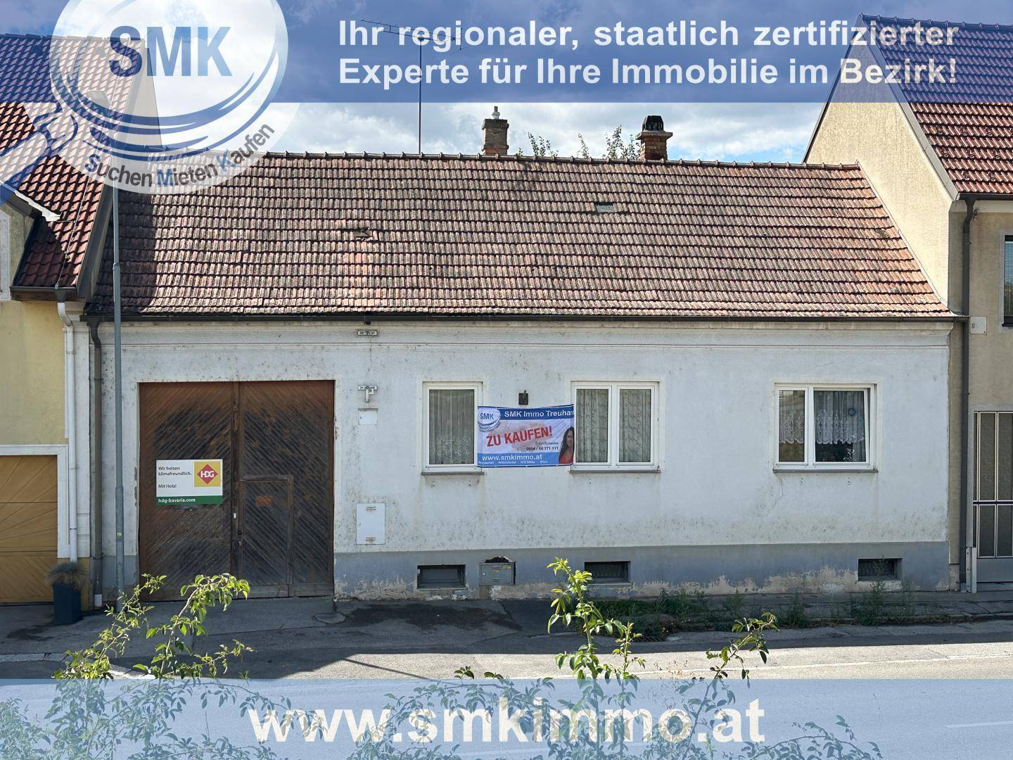 Fassade eines älteren Hauses von der Straße aus gesehen, mit einem Verkaufsschild im Fenster.