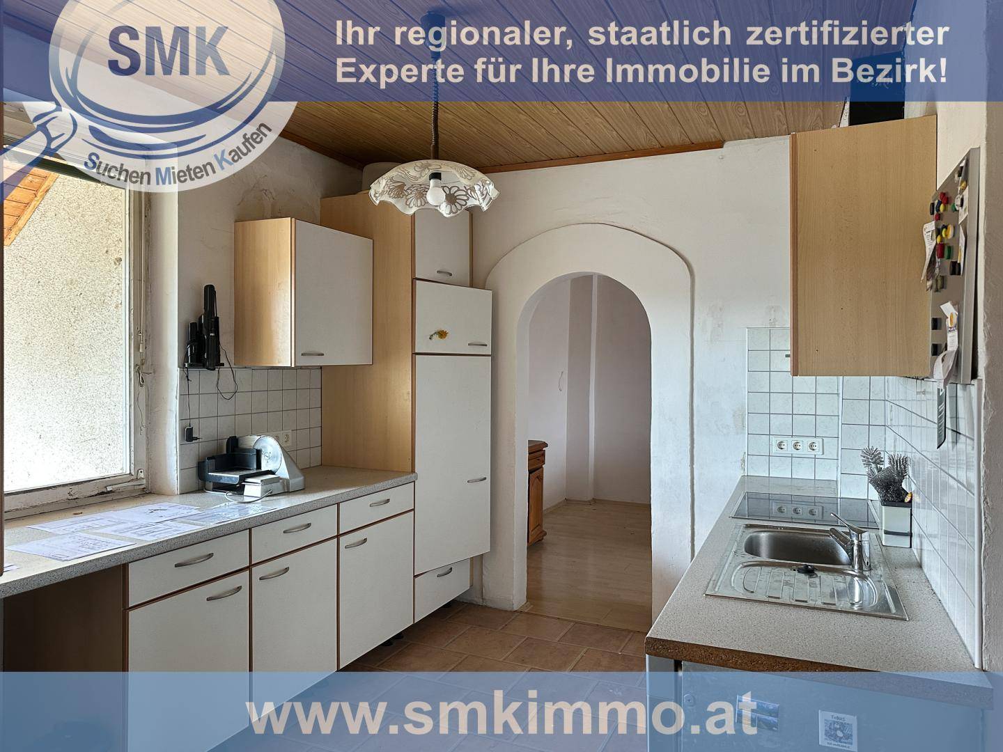 Kleine Küche mit Holzdecke, weißen Schränken und einem Durchgang zu einem weiteren Raum.