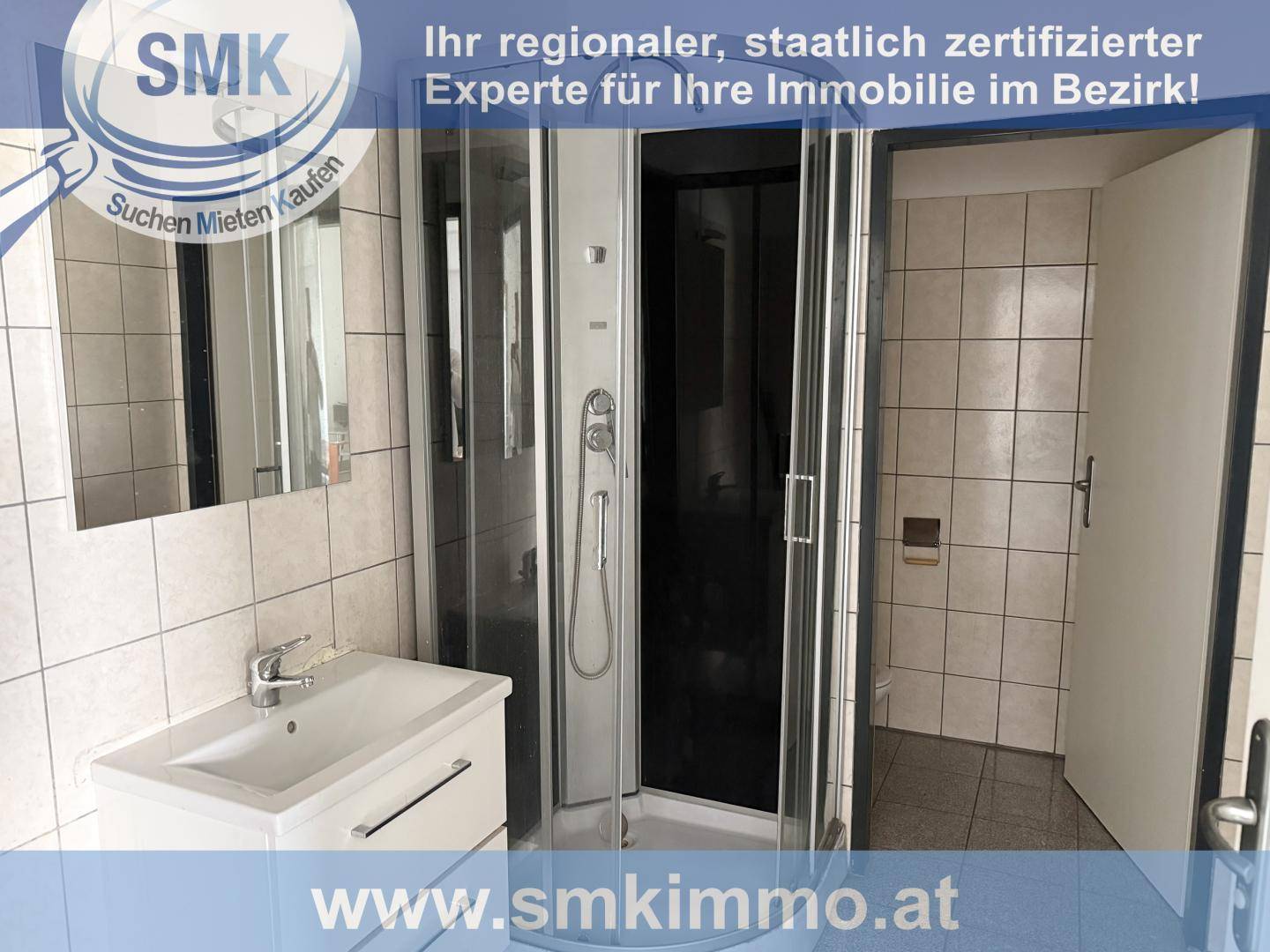 Badezimmer mit Duschkabine, Waschbecken und Spiegel, gefliesten Wänden und einem Durchgang zu einer Toilette.