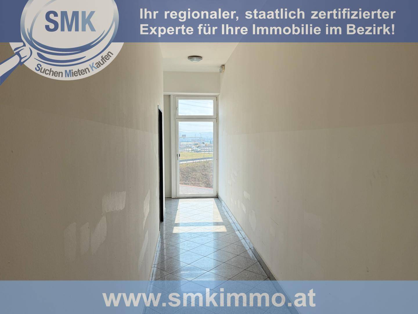 Langer, heller Flur mit Fliesenboden und einer Tür am Ende, die ins Freie oder zu einem Balkon führt.