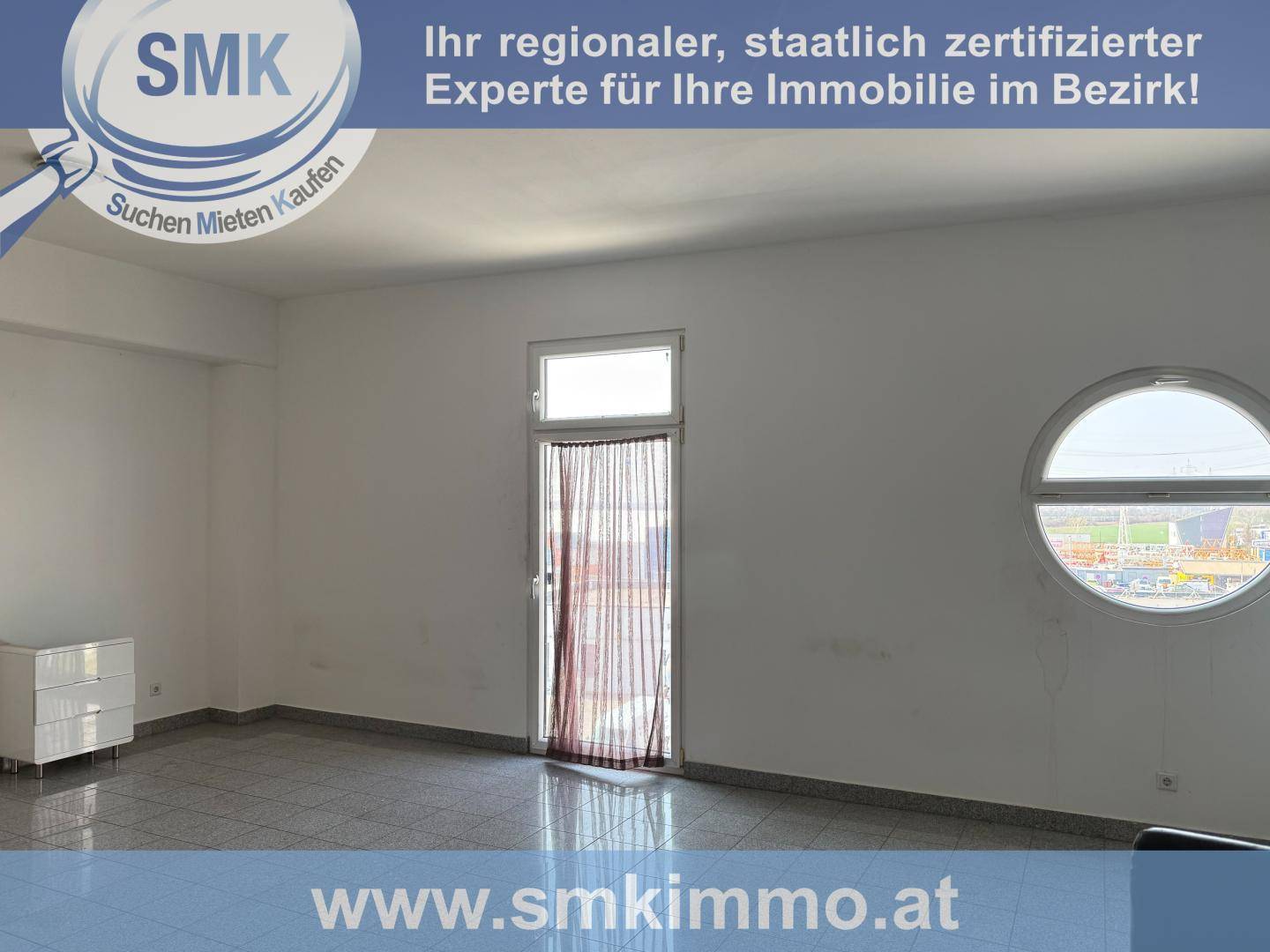 Geräumiger Raum mit Fliesenboden, einem großen Fenster und einem runden Fenster, das viel Tageslicht hereinlässt.