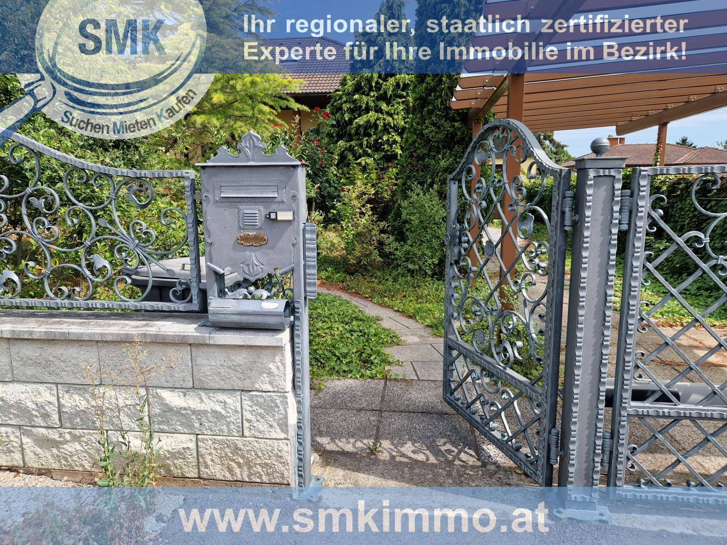 Dekoratives schmiedeeisernes Tor mit Briefkasten am Eingang eines Grundstücks.