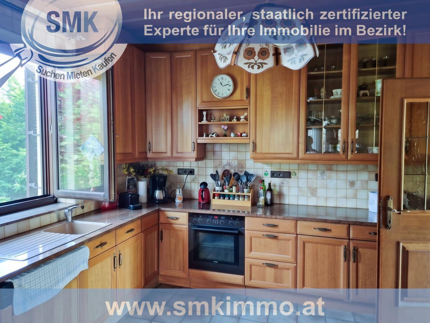 Küche im Landhausstil mit Holzschränken, Fliesenrückwand und großem Fenster.
