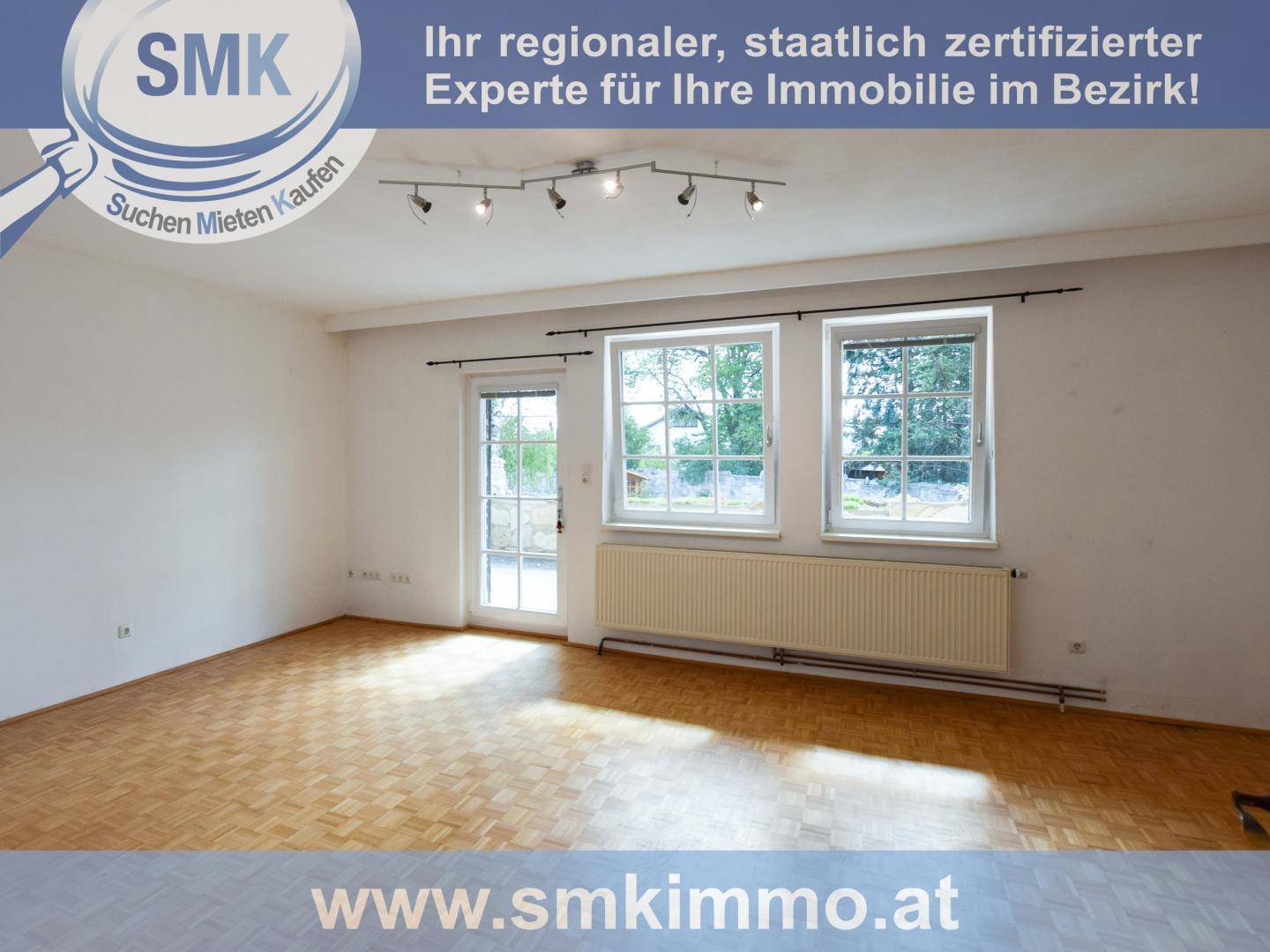 Geräumiger Raum mit Parkettboden, großen Fenstern und Zugang zu einem Außenbereich.