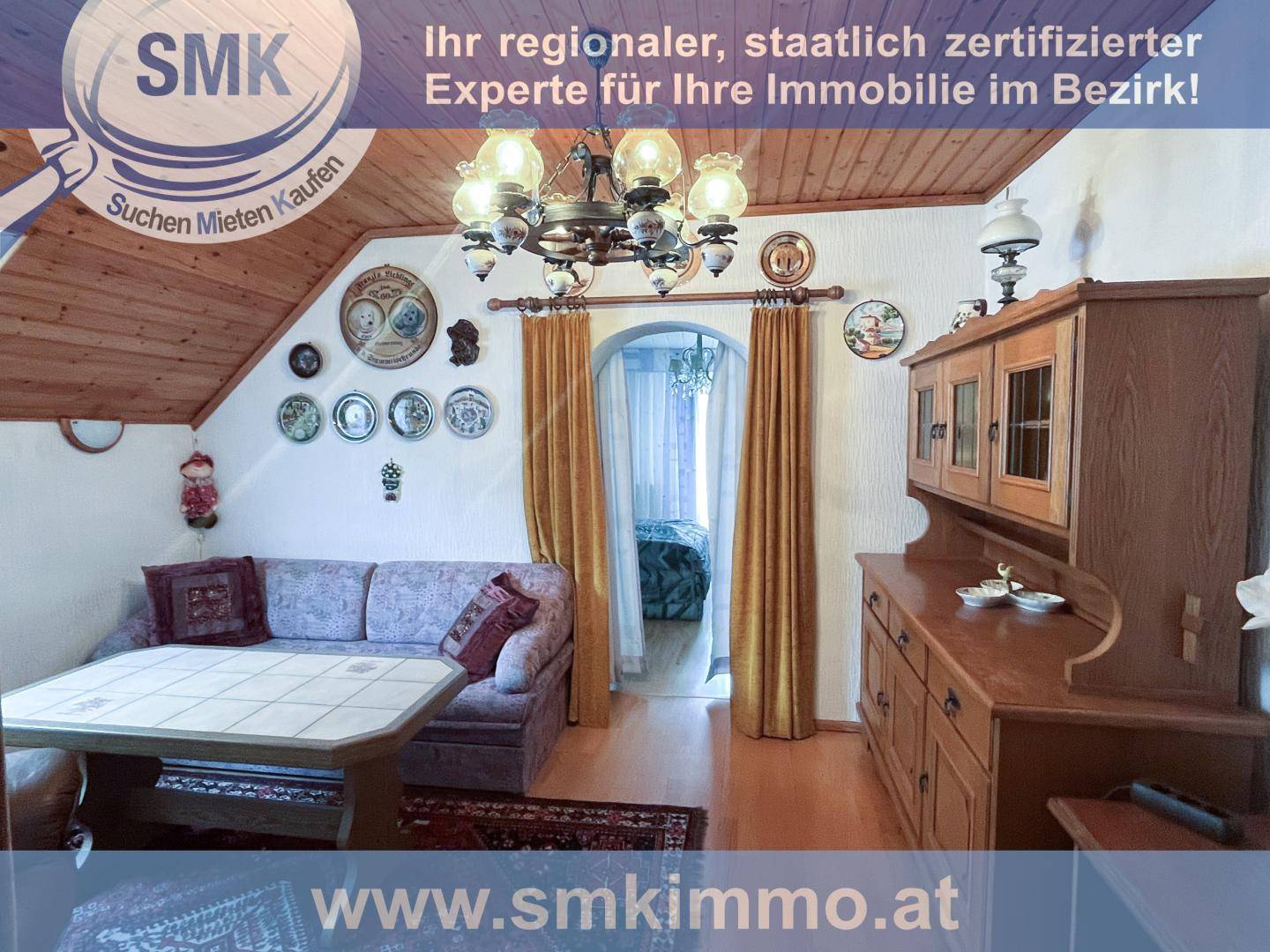 Gemütliches Wohnzimmer mit Sofa, Holzmöbeln und schräger Decke im Dachgeschoss.