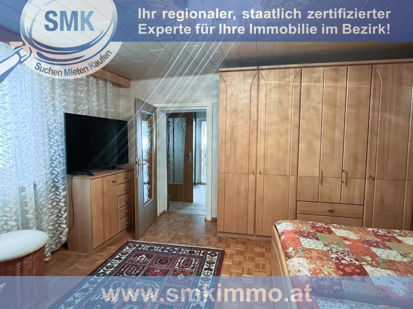 Schlafzimmer mit großem Holzschrank, Doppelbett und Fernseher auf einer Kommode.