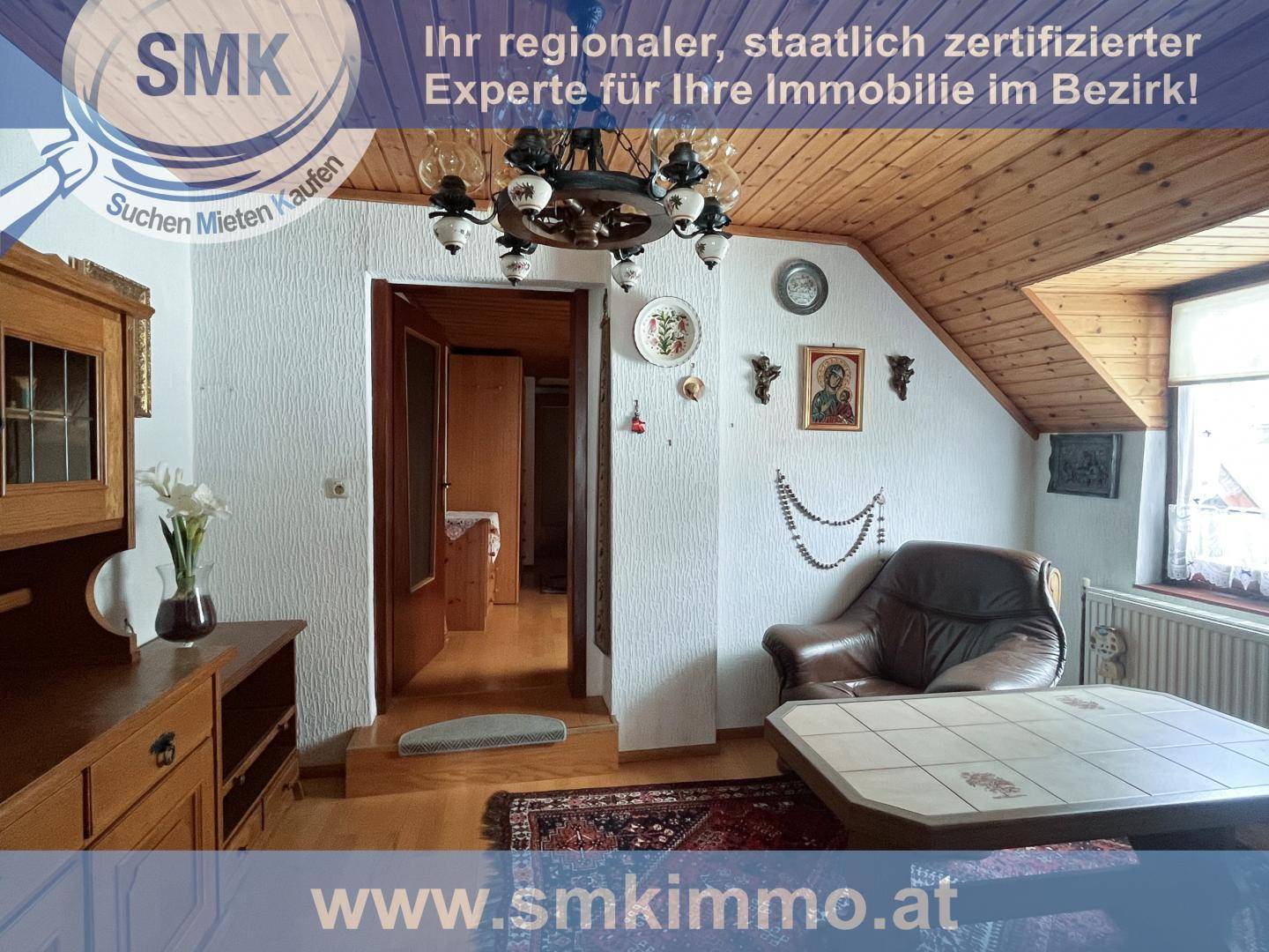 Wohnbereich im Dachgeschoss mit Holzboden, Ledersessel und traditionellen Holzmöbeln.