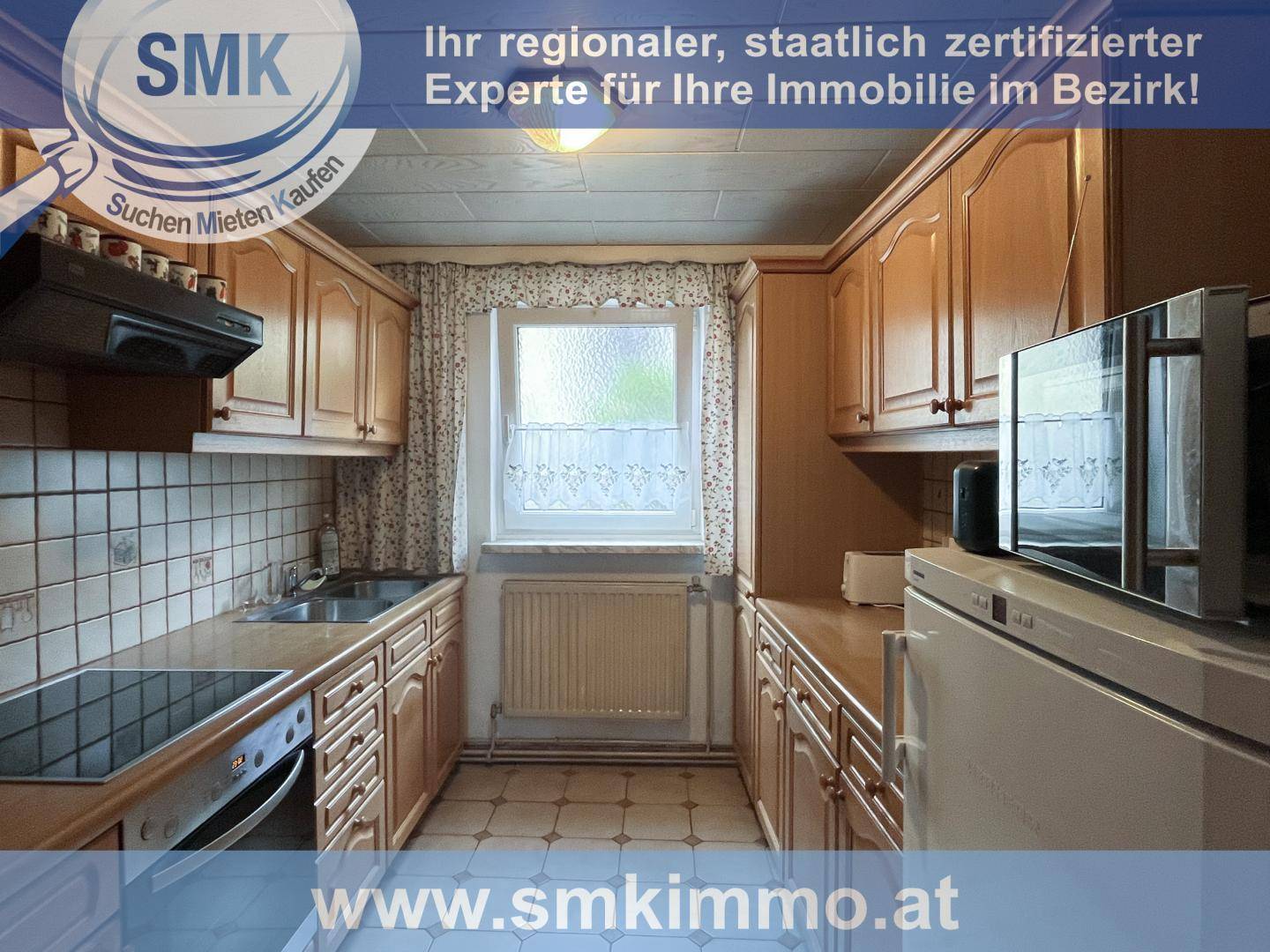 Traditionelle Küche mit hellen Holzschränken, Fliesenboden und einem Fenster über der Spüle.