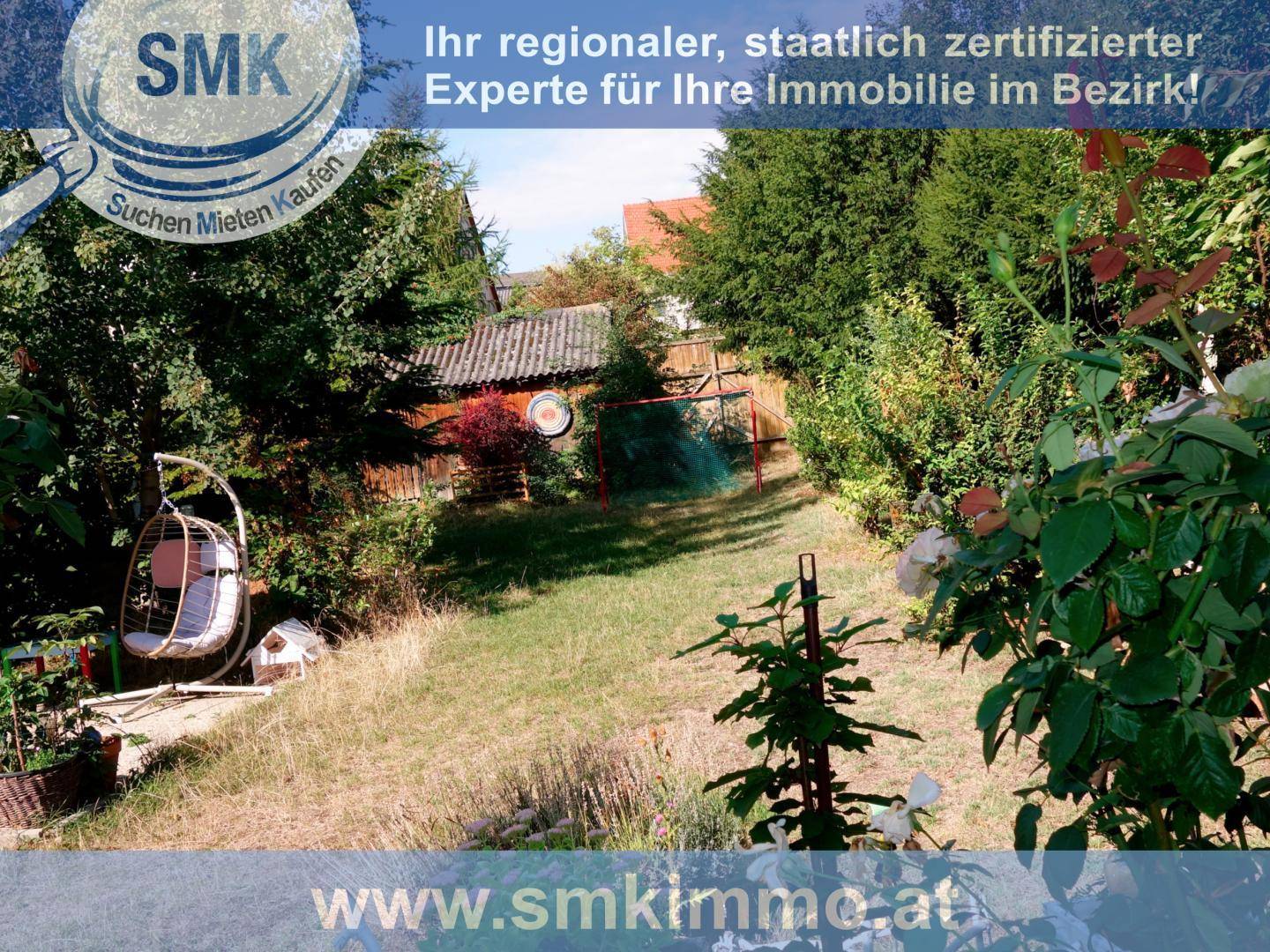 Garten mit Schaukelstuhl, Rasenfläche und blühenden Pflanzen im Vordergrund.