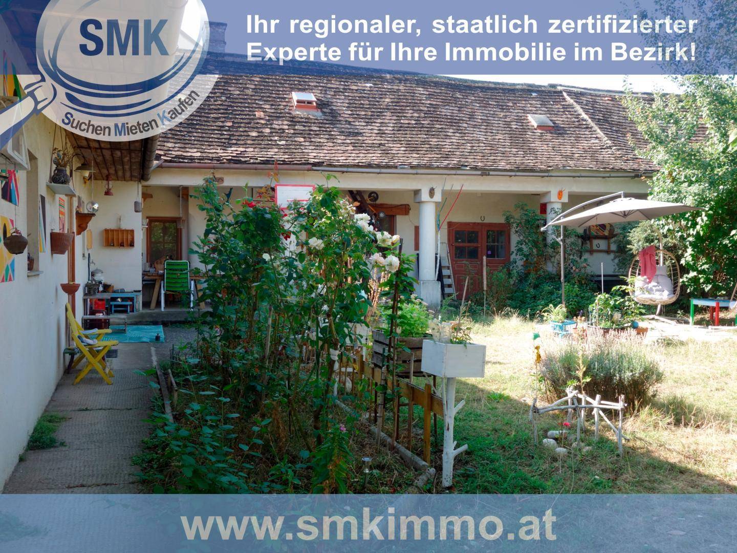 Rückseite des Hauses mit einem naturbelassenen Garten und überdachtem Sitzbereich im Freien.