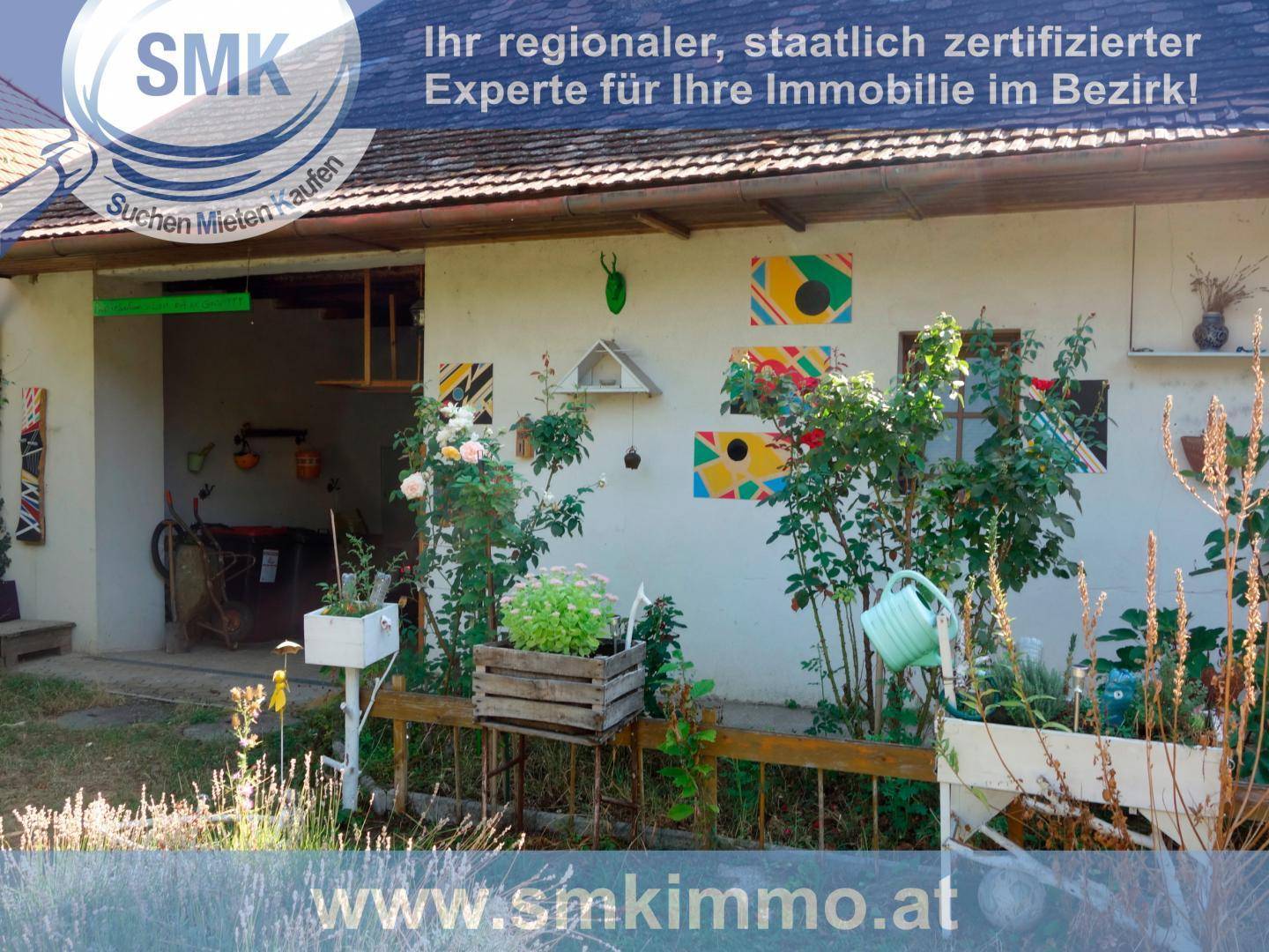 Hausrückseite mit kleinem Gartenbereich, bunten Wanddekorationen und Pflanzen.