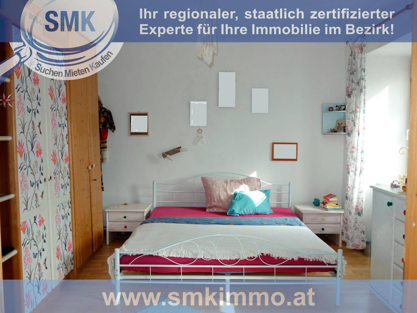 Helles Schlafzimmer mit Doppelbett, Holzschrank und floraler Vorhangdekoration für eine freundliche Atmosphäre.
