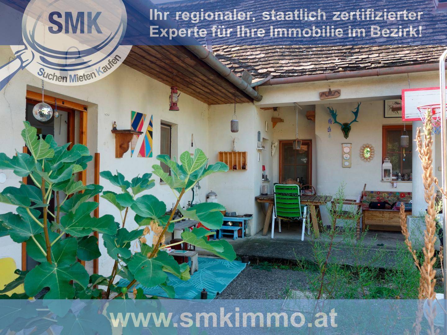Überdachte Terrasse am Haus mit Sitzgelegenheiten und Blick in den grünen Garten.