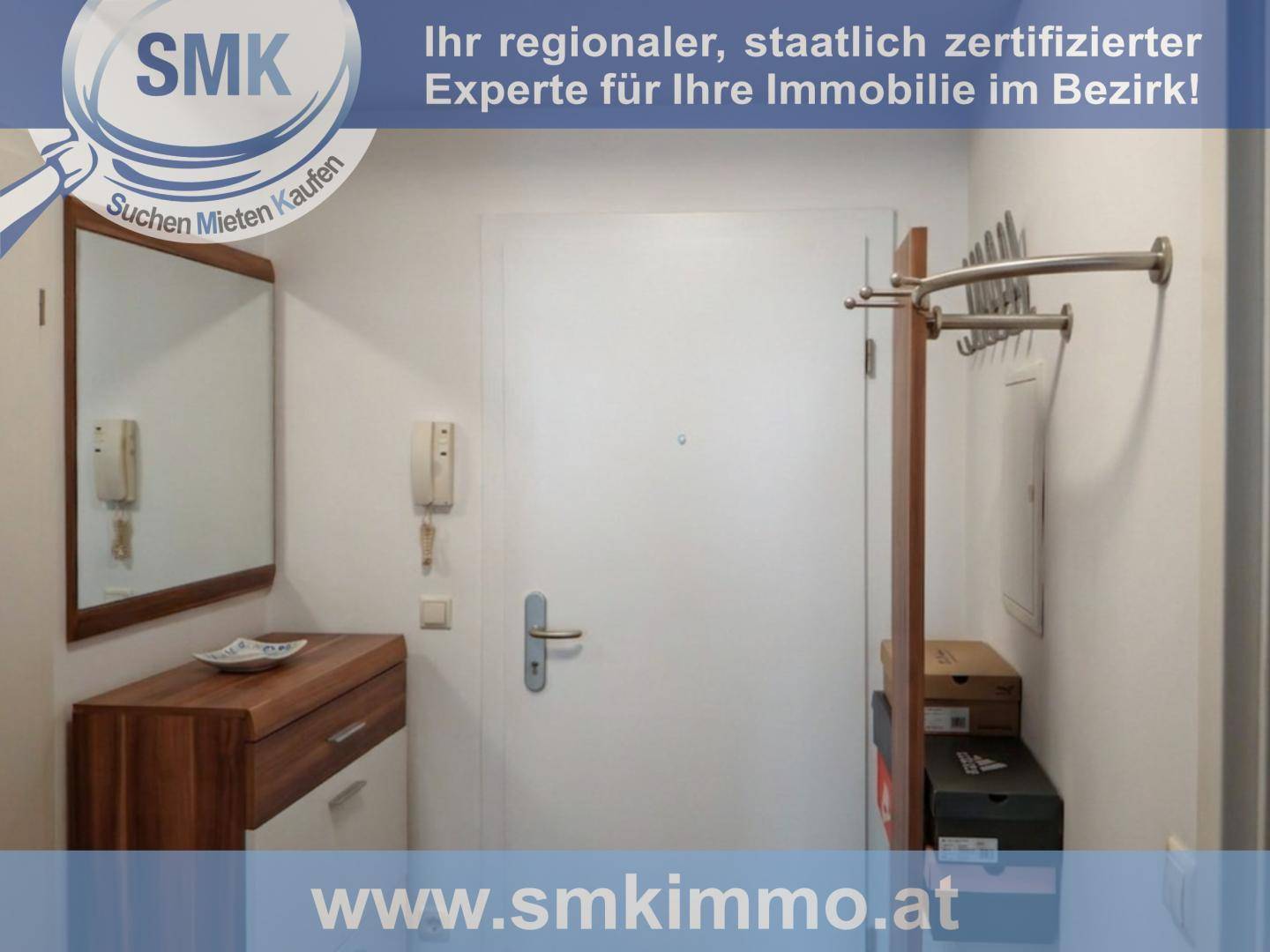 Heller Eingangsbereich mit weißer Tür, Spiegel, Holzkonsole und Garderobe für Besucher.