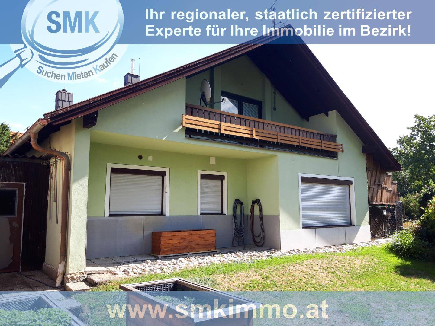 Seitenansicht des Hauses mit einem Balkon im Obergeschoss und Rollläden an den Fenstern.