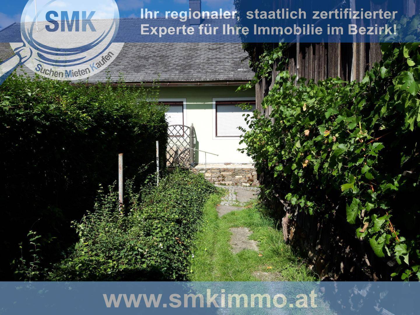 Schmaler Gartenweg umgeben von dichtem Grün und Hecken, der zum Haus führt.