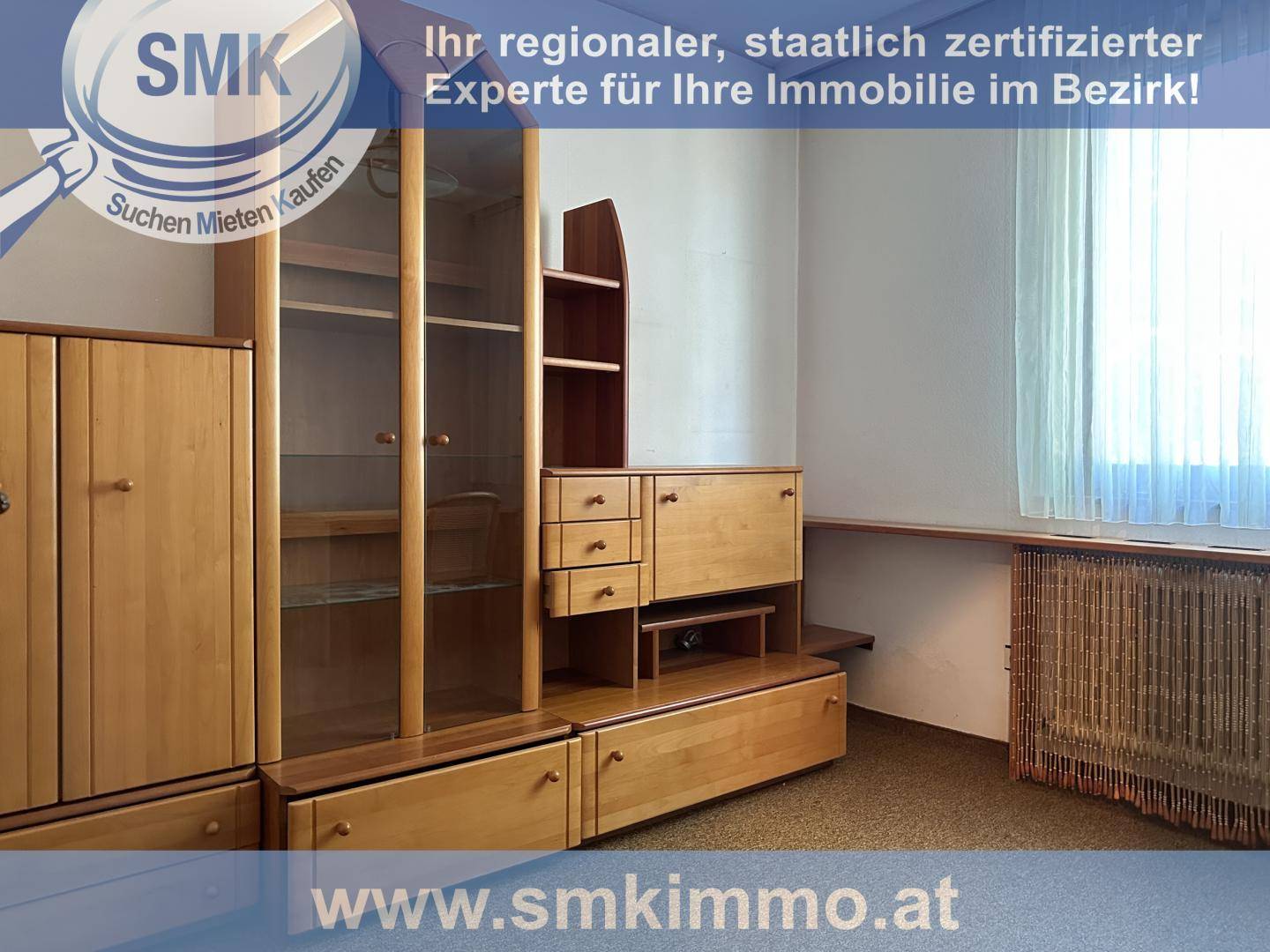 Zimmer mit Holzmöbeln, Regalen und einem Fenster, das viel Tageslicht hereinlässt.