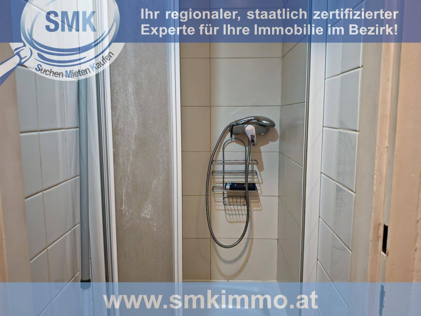 Duschkabine mit hellen Fliesen und Duscharmatur in einem Badezimmer.