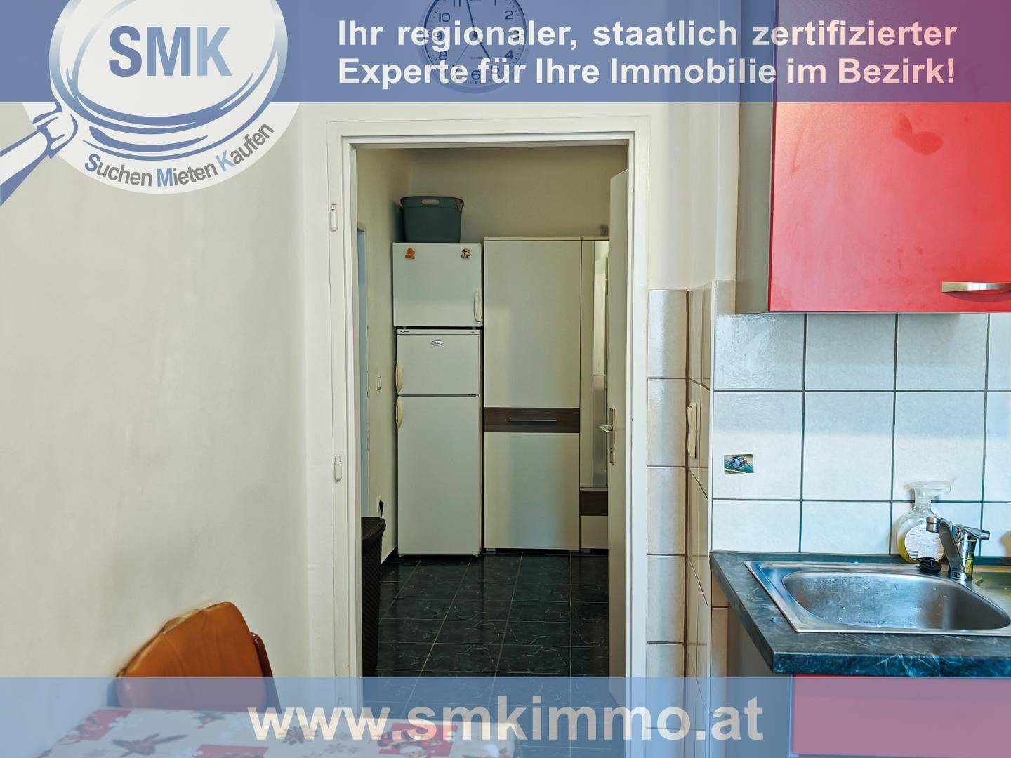Küchenbereich mit roten Schränken und Blick auf Kühlschrank und weiteren Stauraum.