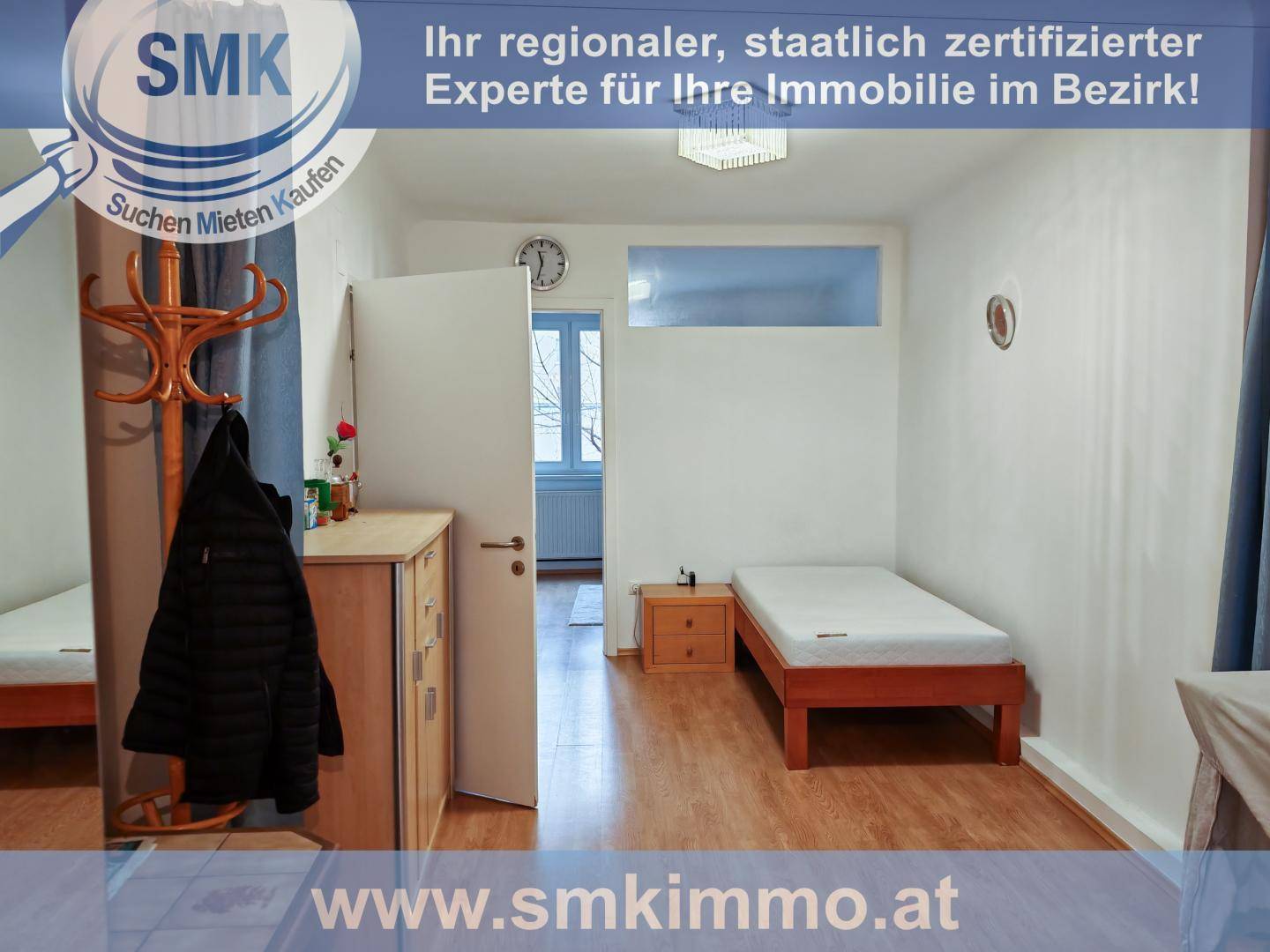 Einfaches Schlafzimmer mit Holzbett, Garderobe und Zugang zu einem weiteren Raum.