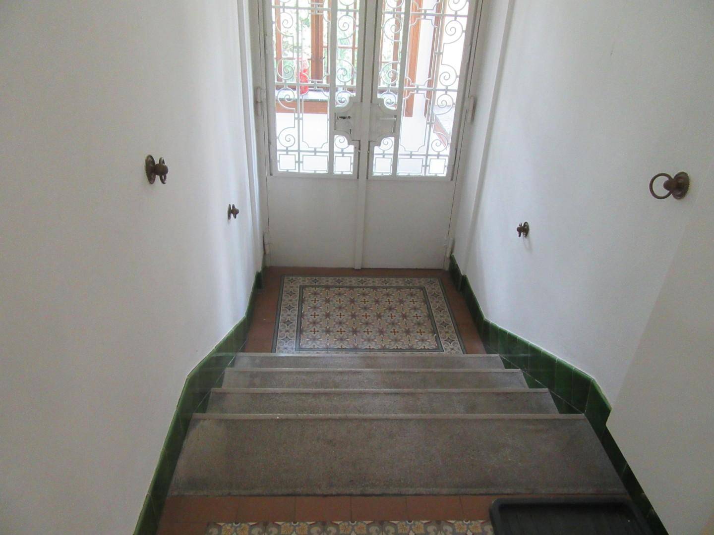 Eingangsbereich mit gefliester Treppe und dekorativer Gittertür, die viel Licht hereinlässt.
