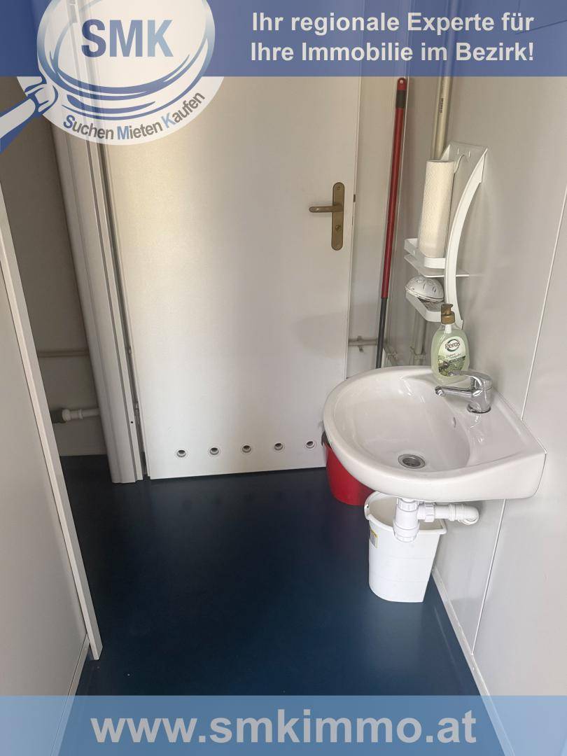 Kleiner Toilettenraum mit Waschbecken und Tür, funktional eingerichtet.