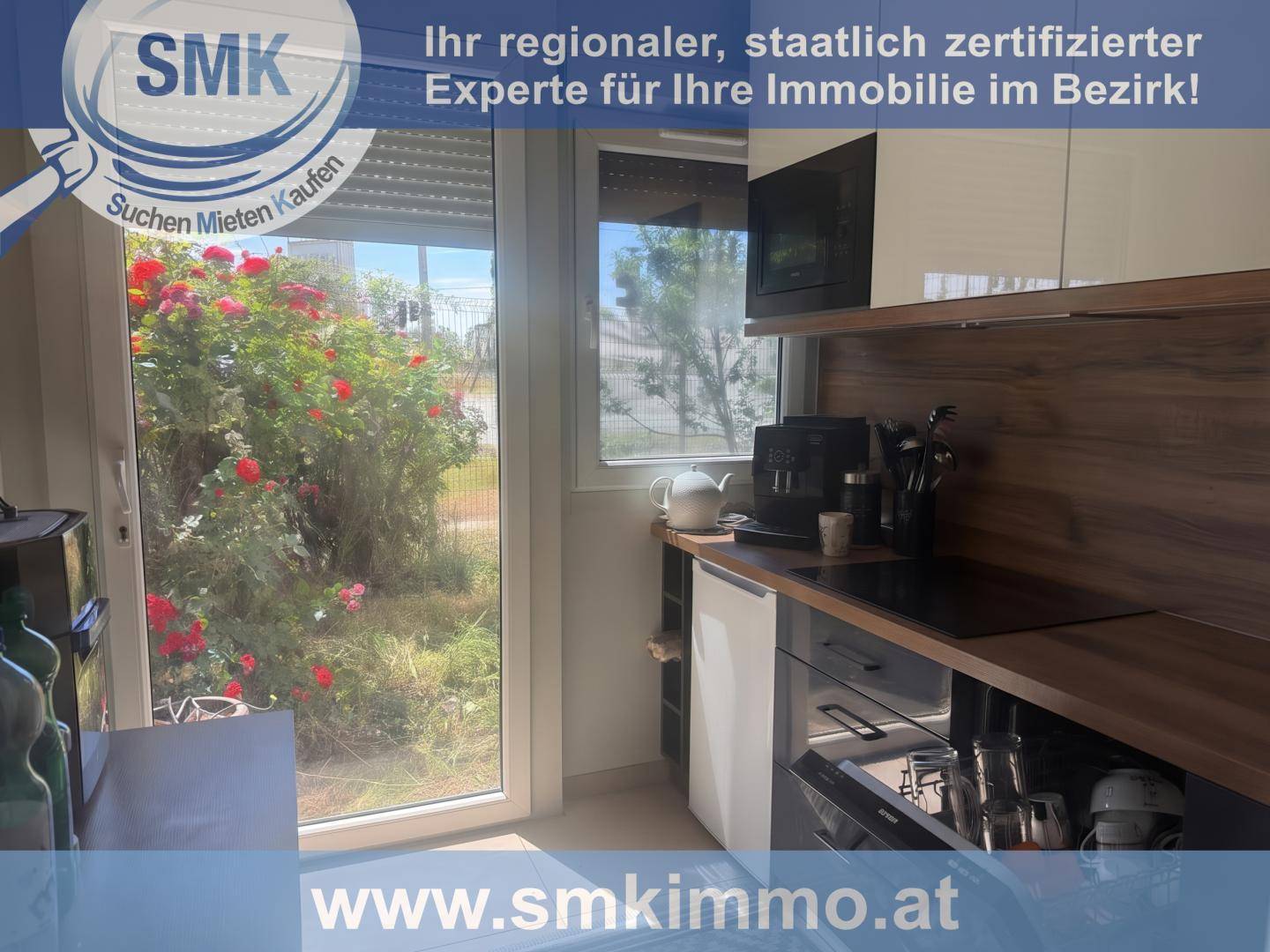 Kleine moderne Küche mit Einbaugeräten, Kaffeemaschine und Blick ins Grüne.
