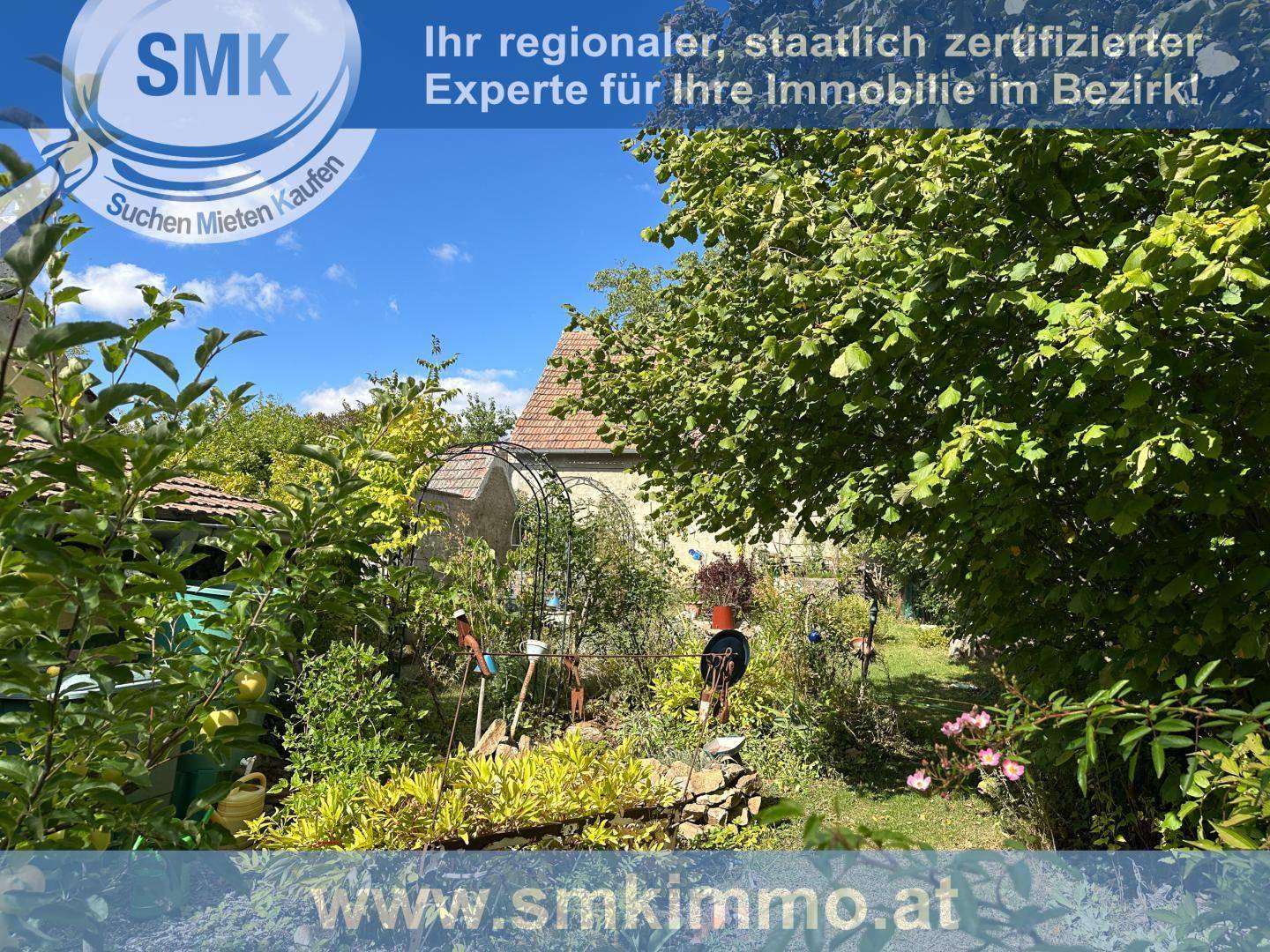 Gepflegter Garten mit verschiedenen Pflanzen, Gartengeräten und Blick auf das Haus.