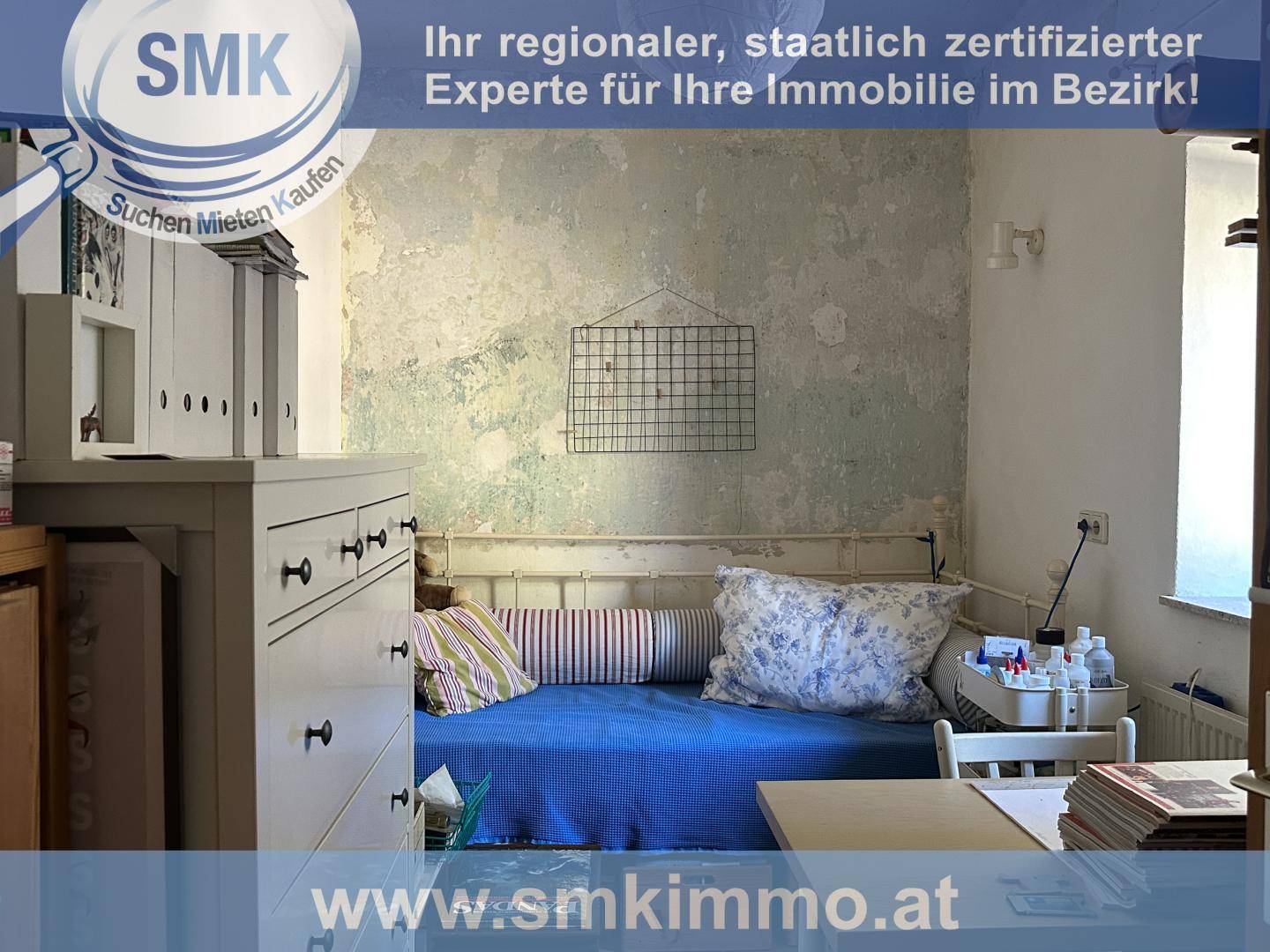 Kleines Zimmer mit Tagesbett, Schreibtisch und einer Wand mit rustikalem Putz.