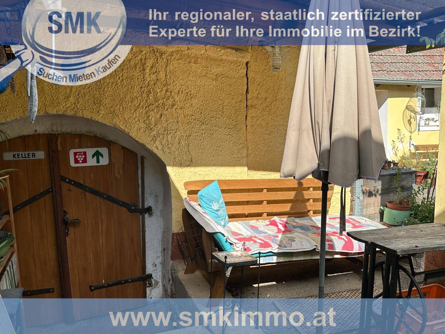 Gemütlicher Sitzbereich im Freien neben einer rustikalen Kellertür.