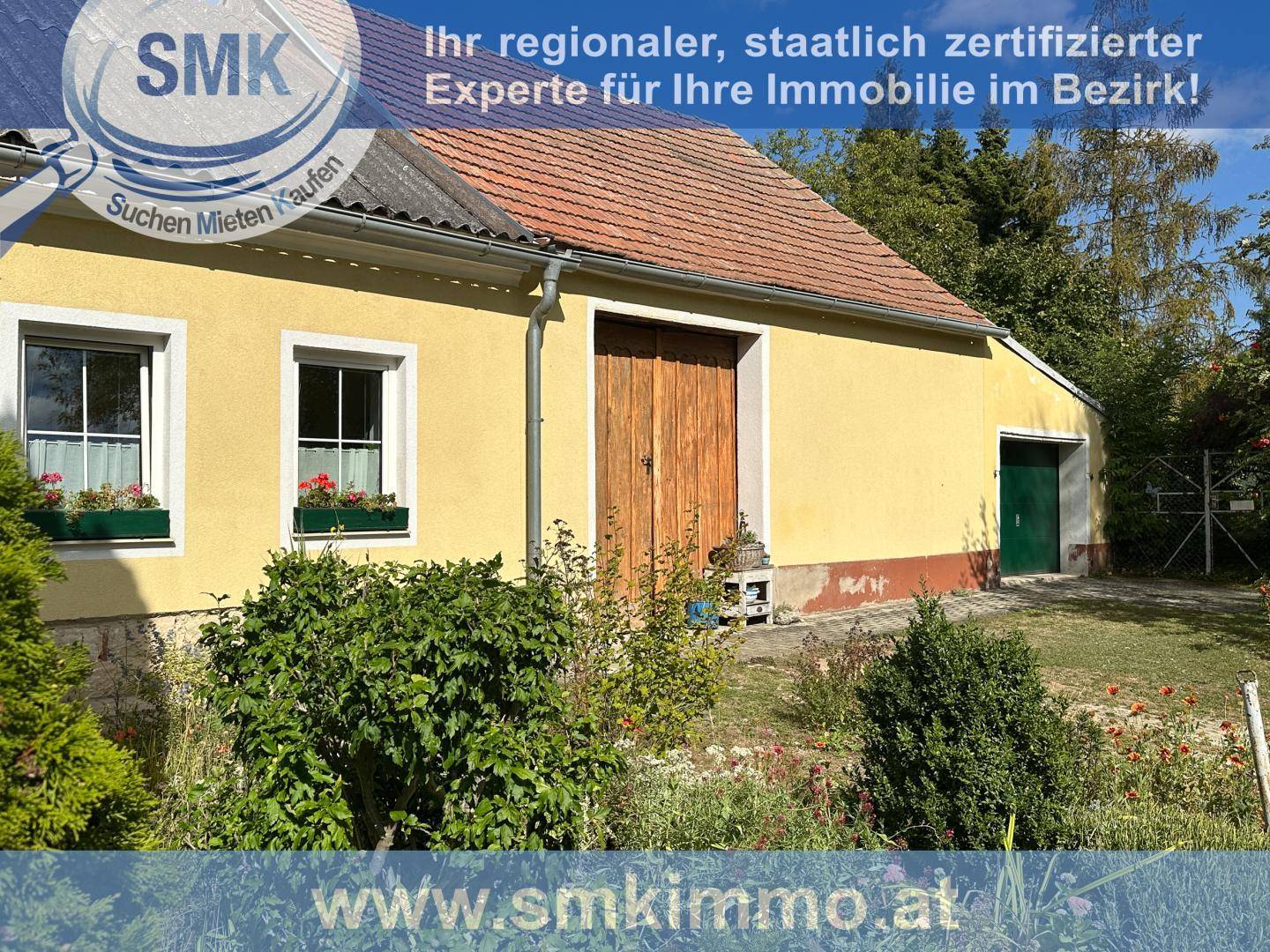 Gelbe Hausfassade mit roten Dachziegeln, Holztür und gepflegtem Vorgarten.