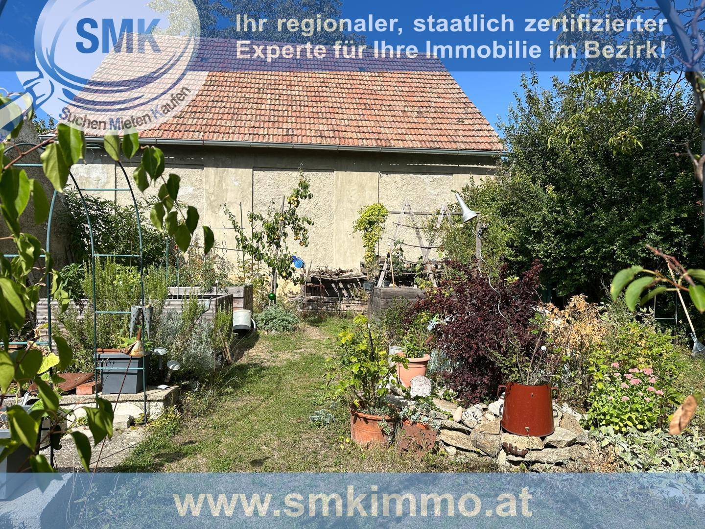 Hinterhofgarten mit einem Pfad, Topfpflanzen und der Rückseite des Hauses.