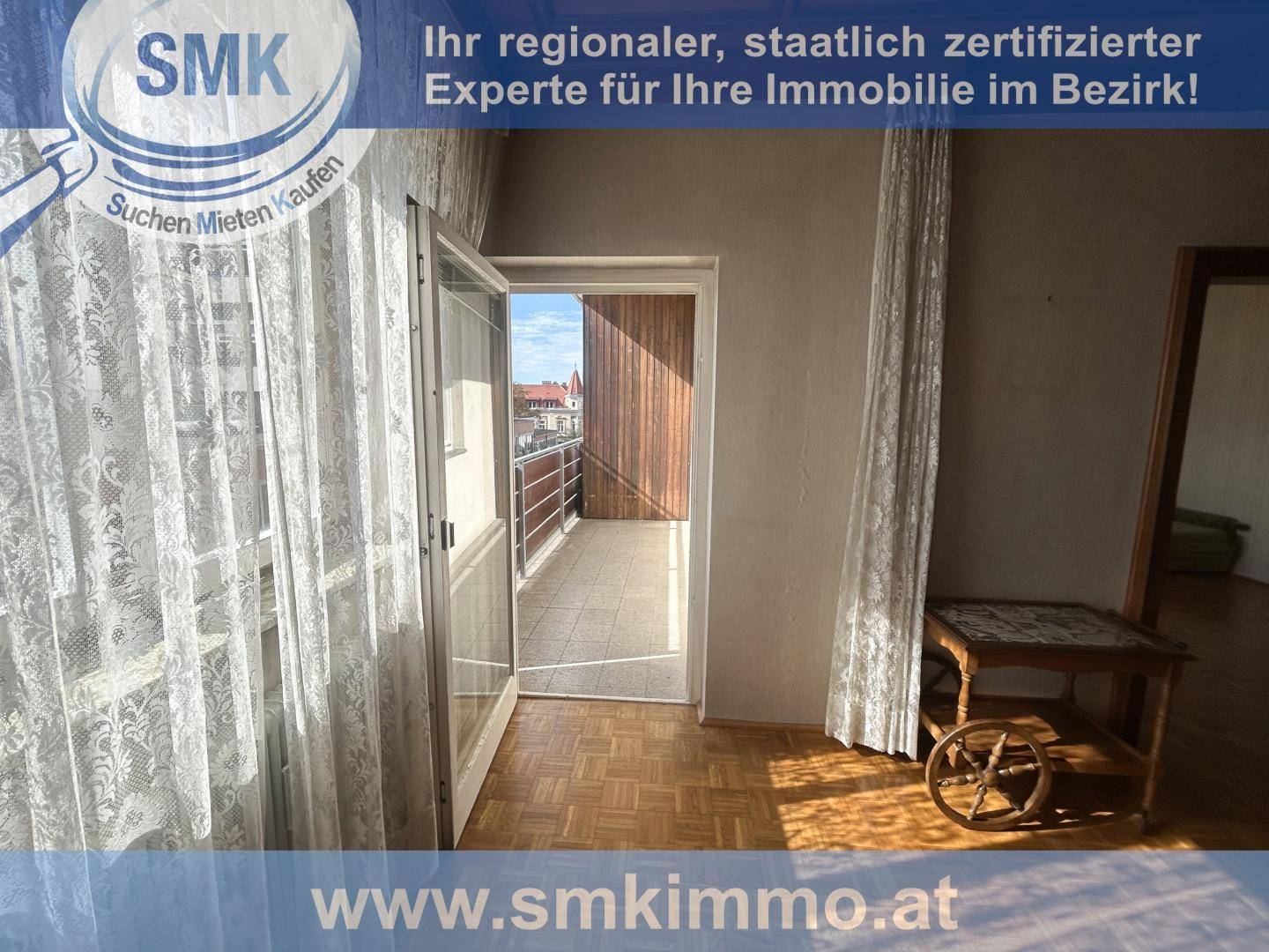 Innenraum mit Parkettboden und einer geöffneten Tür, die den Zugang zu einem Balkon ermöglicht.