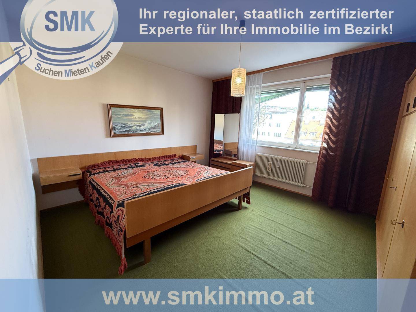 Schlafzimmer mit Doppelbett, Holzmöbeln, grünem Teppichboden und einem Fenster mit Blick nach draußen.