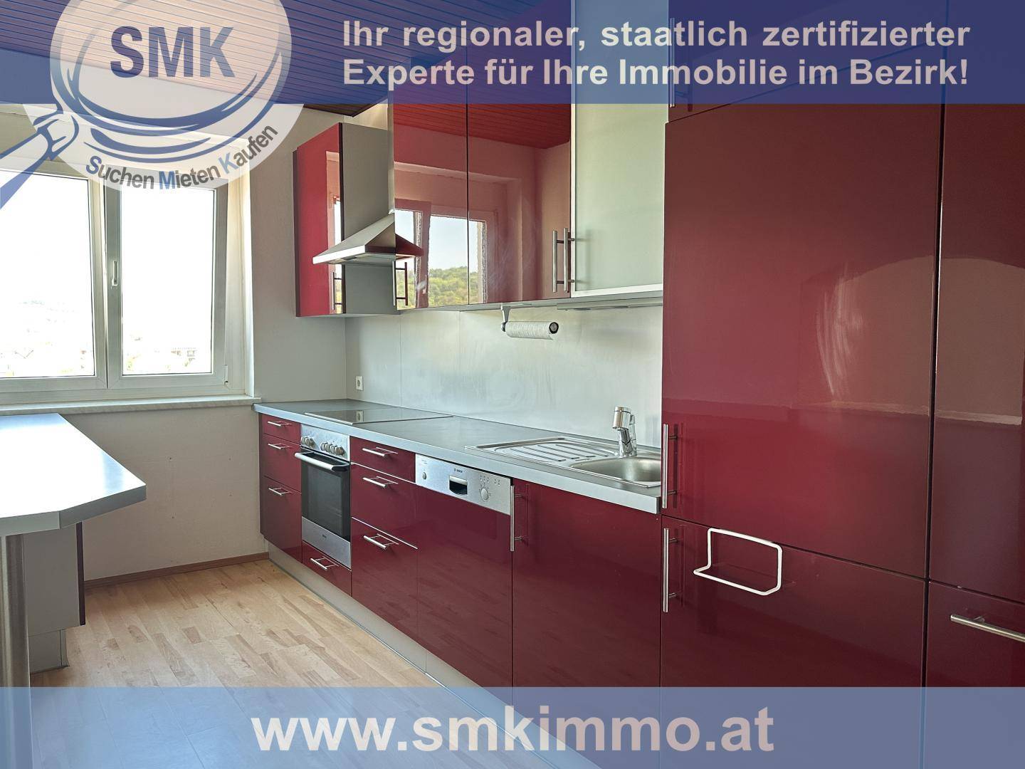 Moderne Küche mit roten Hochglanzfronten, integrierten Geräten und Fenster.