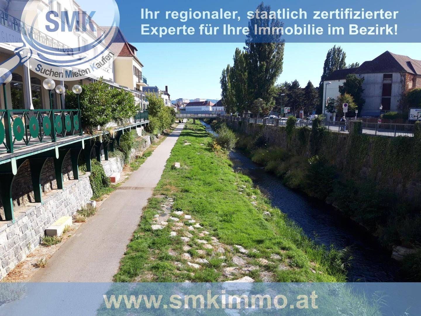 Flusslauf mit grünen Ufern und einem Spazierweg, umgeben von städtischer Bebauung.