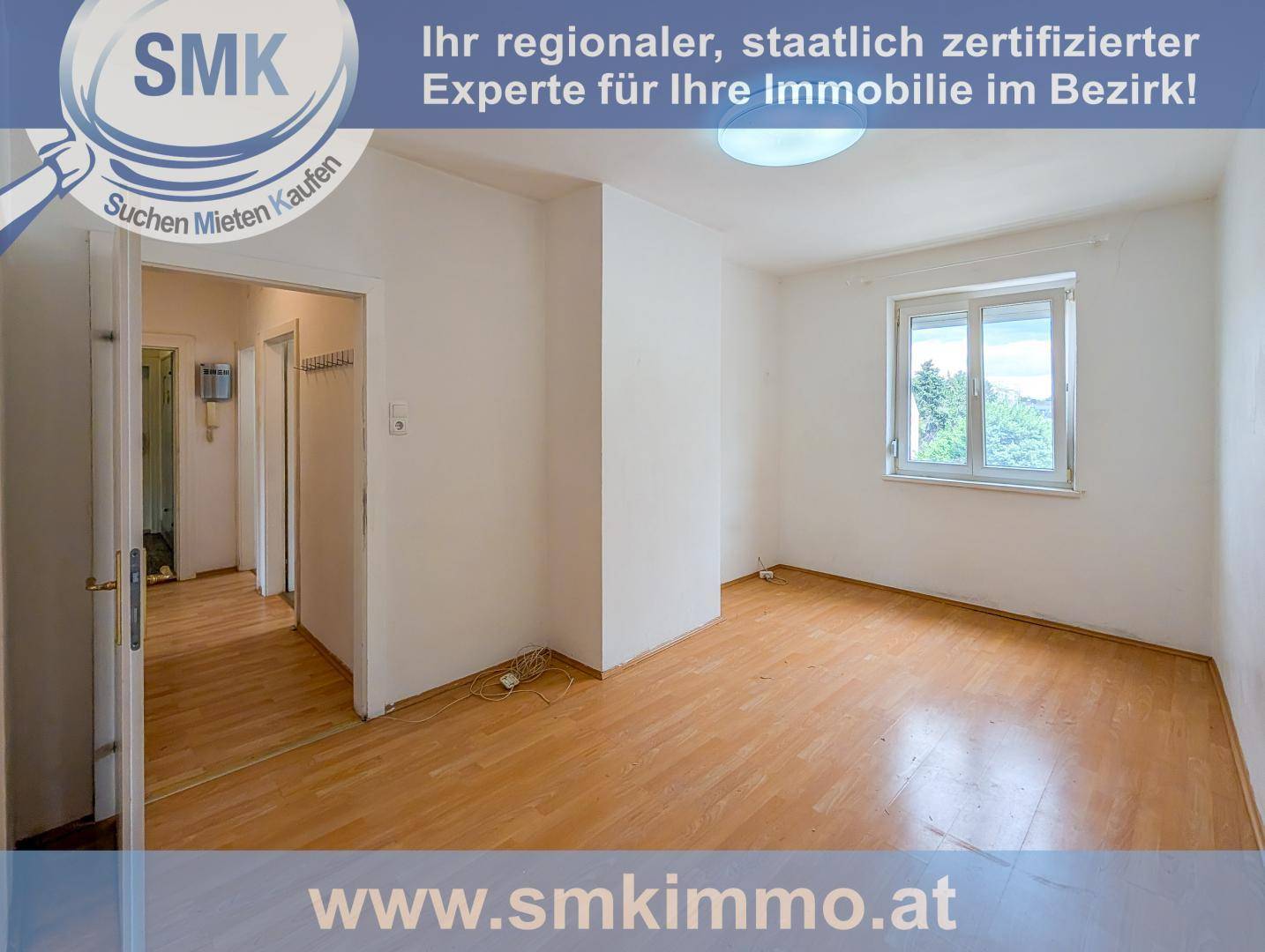 Leerer Raum mit hellem Laminatboden, weißen Wänden und Fenster.