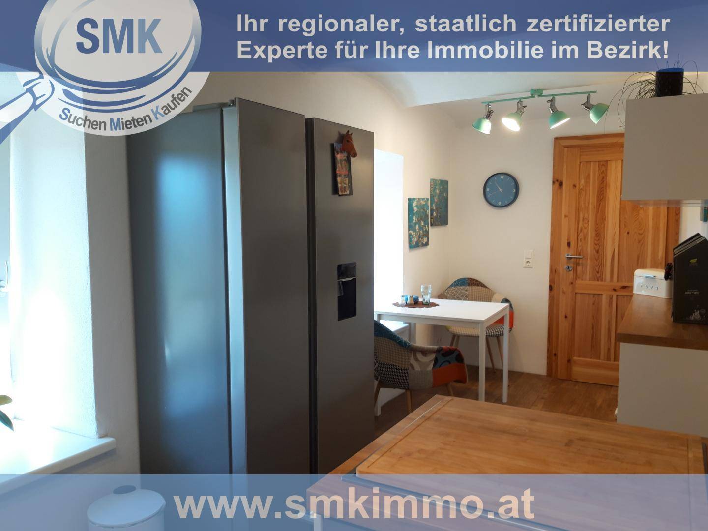 Küche mit großem Kühlschrank, Essbereich und Holzelementen unter Spotlights.