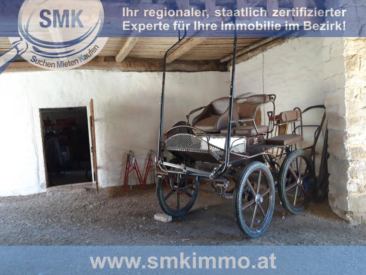 Rustikaler Innenraum einer Scheune mit einem historischen Pferdewagen und Holzbalken.
